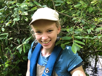 Female ecologist smiling whilst holding a white-clawed crayfish