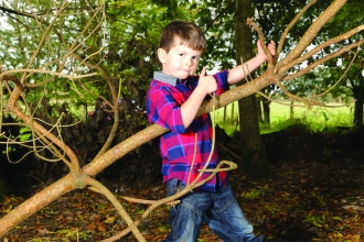 Ruaridh plays guitar on a tree branch