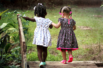 Two girls crossing a wooden bridge holding hands