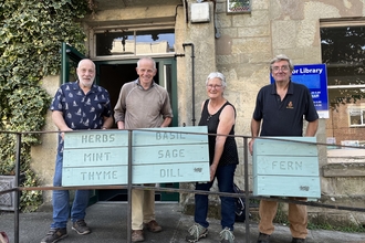 Four people holding up planter signs