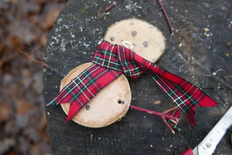 Wood slice snowman with a ribbon scarf and stick arms.