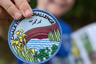 Child holding a Chalk Stream Challenge badge © Katy Seaman