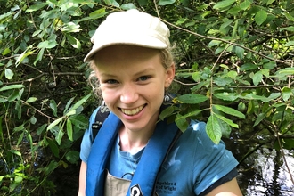 Female ecologist smiling whilst holding a white-clawed crayfish