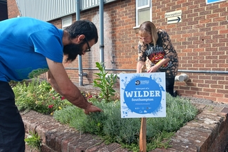 Two people working around a brick planter with a sign reading 'Wilder Southampton'