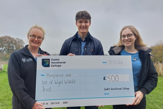 3 people holding a large cheque made out of to Hampshire & Isle of Wight Wildlife Trust for £500