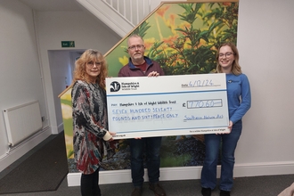 3 people holding a large cheque for £770 made out to Hampshire & Isle of Wight Wildlife Trust