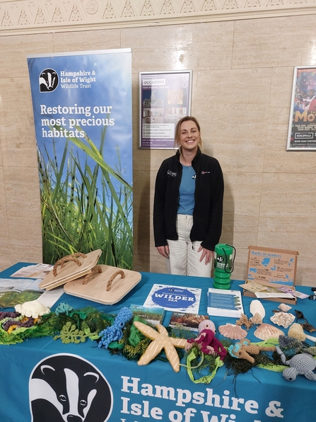 Hampshire & Isle of Wight Wildlife Trust staff member standing by a table displaying various knitted marine animals and plants