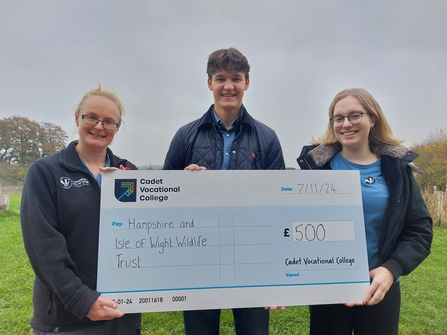 3 people holding a large cheque made out of to Hampshire & Isle of Wight Wildlife Trust for £500