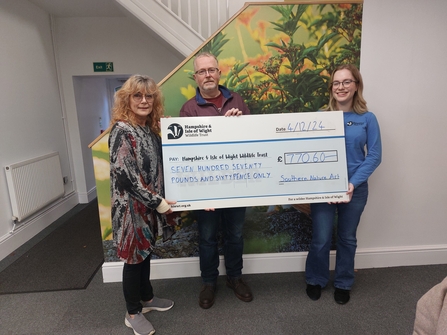 3 people holding a large cheque for £770 made out to Hampshire & Isle of Wight Wildlife Trust